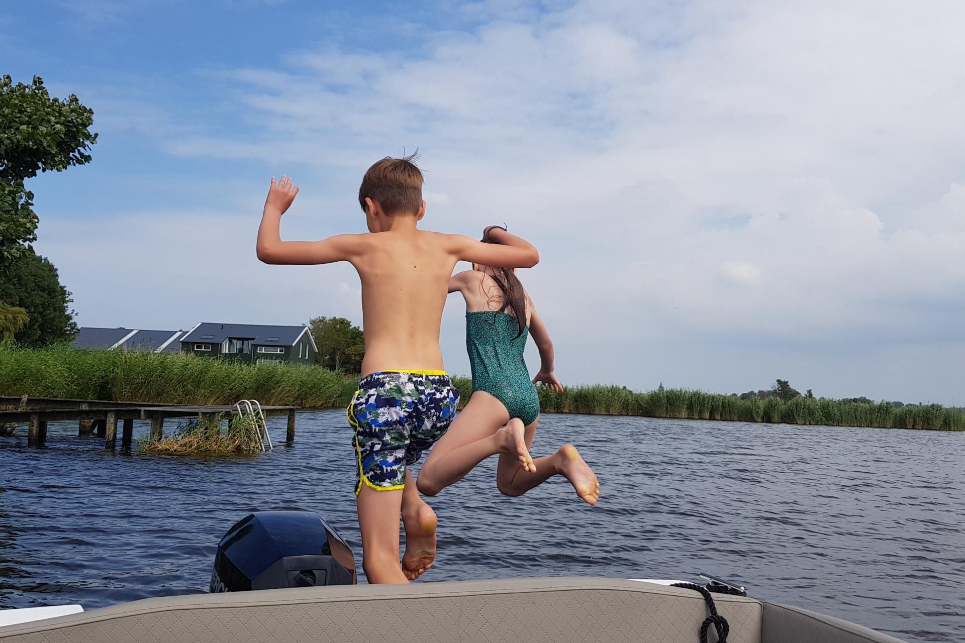 Kinderen springen van een bootje in het water